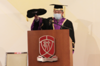 陳教授手持畢業黑帽，做出模仿輕拍畢業生的動作，示意頒授學士學位予每位畢業生，並送上祝賀。